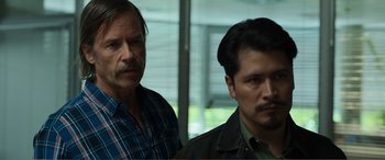 Movie still from “Memory” (2022), directed by Martin Campbell – Two men standing next to each other in front of a window; Close Up shot, Over the shoulder angle