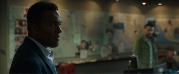 Movie still from “Memory” (2022), directed by Martin Campbell – A man in a blue shirt is in front of a whiteboard; Close Up shot, Over the shoulder angle