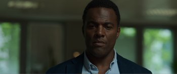 Movie still from “Memory” (2022), directed by Martin Campbell – A person wearing a suit and tie; Close Up shot, Low angle