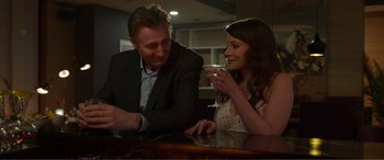 Movie still from “Memory” (2022), directed by Martin Campbell – A man and a woman sitting at a table drinking champagne; Medium shot, Over the shoulder angle
