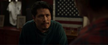 Movie still from “Memory” (2022), directed by Martin Campbell – A person sitting in front of an american flag; Close Up shot, Over the shoulder angle