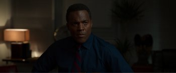 Movie still from “Memory” (2022), directed by Martin Campbell – A man wearing a blue shirt and a red tie; Close Up shot, Over the shoulder angle