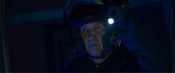 Movie still from “Memory” (2022), directed by Martin Campbell – A man wearing a motorcycle helmet with a light on it; Close Up shot, Over the shoulder angle