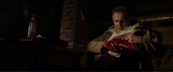 Movie still from “Memory” (2022), directed by Martin Campbell – A man sitting in front of a brick fireplace; Medium shot, Low angle