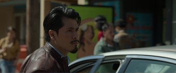 Movie still from “Memory” (2022), directed by Martin Campbell – A person with a car in the background; Close Up shot, Over the shoulder angle