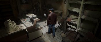Movie still from “Memory” (2022), directed by Martin Campbell – A man standing in an abandoned room looking back; Wide shot, High angle