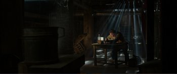 Movie still from “Memory” (2022), directed by Martin Campbell – A man sitting at a table in a dark room; Wide shot, High angle
