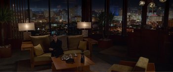 Movie still from “Memory” (2022), directed by Martin Campbell – A man sitting on a couch in a living room; Extreme Wide shot, High angle