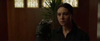 Movie still from “Memory” (2022), directed by Martin Campbell – A woman in a black shirt holding up a gun; Close Up shot, Over the shoulder angle