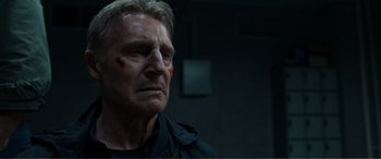 Movie still from “Memory” (2022), directed by Martin Campbell – An older man with a bandage on his face; Close Up shot, Low angle