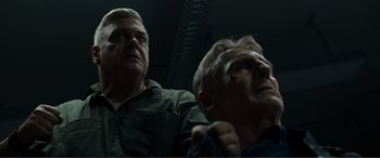 Movie still from “Memory” (2022), directed by Martin Campbell – Two men looking up at the ceiling of a building; Close Up shot, Low angle