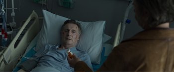 Movie still from “Memory” (2022), directed by Martin Campbell – An older man laying in a hospital bed with bandages on his face; Close Up shot, Over the shoulder angle