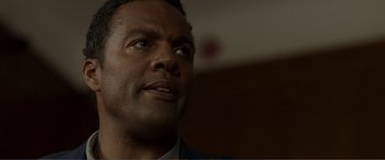 Movie still from “Memory” (2022), directed by Martin Campbell – A person wearing a suit looking up; Close Up shot, Over the shoulder angle