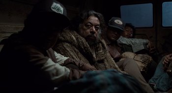 Movie still from “Men in Black” (1997), directed by Barry Sonnenfeld – A group of men sitting next to each other on the ground; Medium shot, Over the shoulder angle