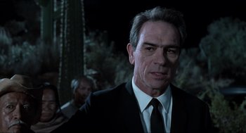Movie still from “Men in Black” (1997), directed by Barry Sonnenfeld – A person wearing a suit and tie; Close Up shot, Over the shoulder angle