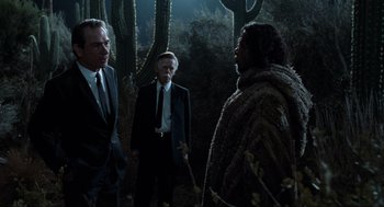 Movie still from “Men in Black” (1997), directed by Barry Sonnenfeld – A group of men standing next to each other in the dark; Medium shot, Over the shoulder angle