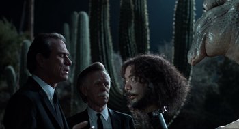 Movie still from “Men in Black” (1997), directed by Barry Sonnenfeld – A group of men standing next to each other in front of cacti; Close Up shot, Over the shoulder angle