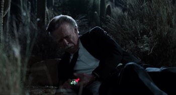 Movie still from “Men in Black” (1997), directed by Barry Sonnenfeld – An older man looking at a cell phone; Medium shot, High angle