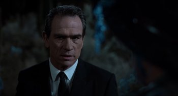 Movie still from “Men in Black” (1997), directed by Barry Sonnenfeld – A man in a black suit and white tie; Close Up shot, Over the shoulder angle