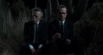 Movie still from “Men in Black” (1997), directed by Barry Sonnenfeld – A couple of men sitting next to each other in suits; Medium shot, High angle