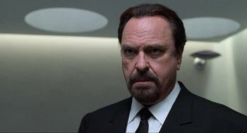 Movie still from “Men in Black” (1997), directed by Barry Sonnenfeld – A man in a black suit and a white tie; Close Up shot, Low angle