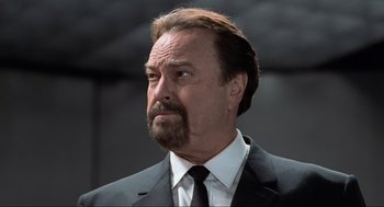 Movie still from “Men in Black” (1997), directed by Barry Sonnenfeld – A man in a suit and tie looking to his left; Close Up shot, Low angle