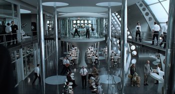 Movie still from “Men in Black” (1997), directed by Barry Sonnenfeld – People are sitting at tables in a large room; Extreme Wide shot, High angle