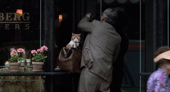 Movie still from “Men in Black” (1997), directed by Barry Sonnenfeld – A man with a cat sitting in a leather bag; Medium shot, Over the shoulder angle