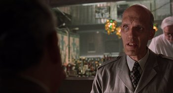 Movie still from “Men in Black” (1997), directed by Barry Sonnenfeld – A man in a suit and tie in front of a bar; Close Up shot, Low angle