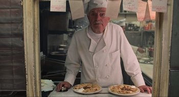 Movie still from “Men in Black” (1997), directed by Barry Sonnenfeld – A man wearing a chef's hat standing in a kitchen; Medium shot, Low angle