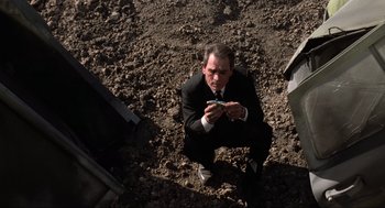 Movie still from “Men in Black” (1997), directed by Barry Sonnenfeld – A man in a suit and tie looking at a cell phone; Medium shot, High angle