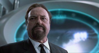 Movie still from “Men in Black” (1997), directed by Barry Sonnenfeld – A man in a suit and tie looking at the camera; Close Up shot, Low angle