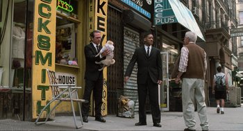 Movie still from “Men in Black” (1997), directed by Barry Sonnenfeld – A man holding a teddy bear while standing next to two other men; Wide shot, Low angle