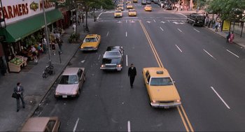 Movie still from “Men in Black” (1997), directed by Barry Sonnenfeld – A man is crossing the street in front of taxis; Extreme Wide shot, High angle