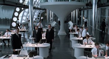 Movie still from “Men in Black” (1997), directed by Barry Sonnenfeld – A group of men in suits standing in a room; Wide shot, High angle