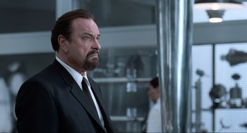 Movie still from “Men in Black” (1997), directed by Barry Sonnenfeld – A man in a suit and tie standing in front of a wall; Close Up shot, Low angle
