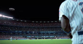 Movie still from “Men in Black” (1997), directed by Barry Sonnenfeld – A baseball player standing on top of a baseball field at night; Extreme Wide shot, Low angle