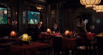 Movie still from “Men in Black 3” (2012), directed by Barry Sonnenfeld – Two men sitting at a table in front of a television; Wide shot, Over the shoulder angle