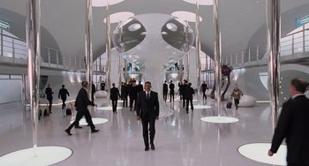 Movie still from “Men in Black 3” (2012), directed by Barry Sonnenfeld – A man in a suit and tie standing in front of a group of people; Wide shot, High angle