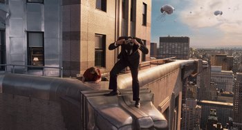 Movie still from “Men in Black 3” (2012), directed by Barry Sonnenfeld – A man standing on top of a building looking through binoculars; Wide shot, Low angle