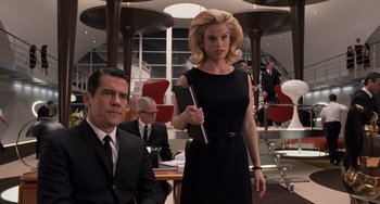 Movie still from “Men in Black 3” (2012), directed by Barry Sonnenfeld – A man and a woman in a black dress in a room; Medium shot, Low angle