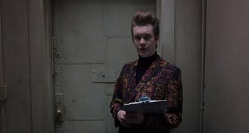 Movie still from “Men in Black 3” (2012), directed by Barry Sonnenfeld – A man in a suit holding a box of cake; Medium shot, Low angle