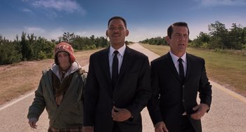 Movie still from “Men in Black 3” (2012), directed by Barry Sonnenfeld – Two men and a woman in a suit and tie on the side of a road; Medium shot, Low angle