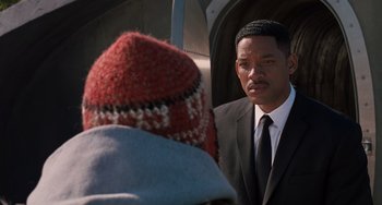 Movie still from “Men in Black 3” (2012), directed by Barry Sonnenfeld – A man in a suit and tie next to another man in a hat; Close Up shot, Over the shoulder angle