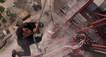 Movie still from “Men in Black 3” (2012), directed by Barry Sonnenfeld – A man in a suit and tie holding onto a pole; Wide shot, Overhead angle