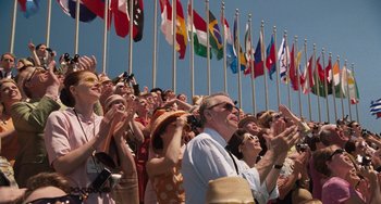 Movie still from “Men in Black 3” (2012), directed by Barry Sonnenfeld – A group of people standing next to each other in front of flags; Wide shot, Low angle