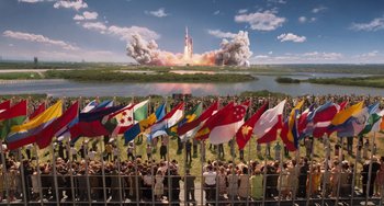 Movie still from “Men in Black 3” (2012), directed by Barry Sonnenfeld – A group of people standing in front of a large group of flags; Extreme Wide shot, High angle