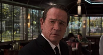 Movie still from “Men in Black 3” (2012), directed by Barry Sonnenfeld – A man in a suit and tie in front of a restaurant; Close Up shot, Over the shoulder angle