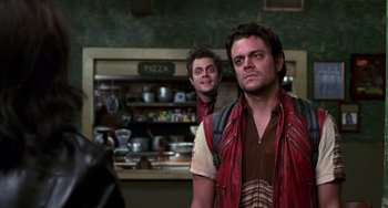 Movie still from “Men in Black II” (2002), directed by Barry Sonnenfeld – Two men are standing in front of a pizza shop; Medium shot, Over the shoulder angle