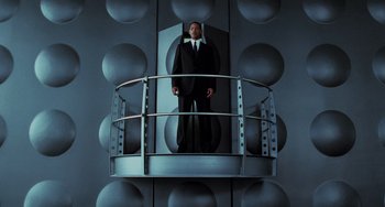 Movie still from “Men in Black II” (2002), directed by Barry Sonnenfeld – A man in a suit and tie standing on a platform; Wide shot, Low angle